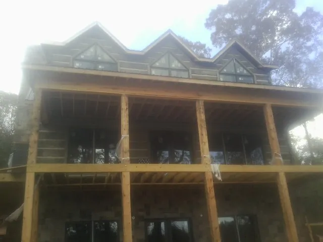 Dormers and porch framing on a large log home under construction — Roof Coating work by our crew in Millington